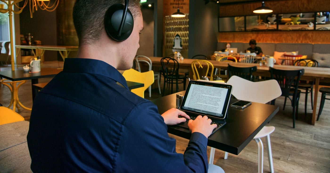 Person using noise canceling headphones at a remote work desk