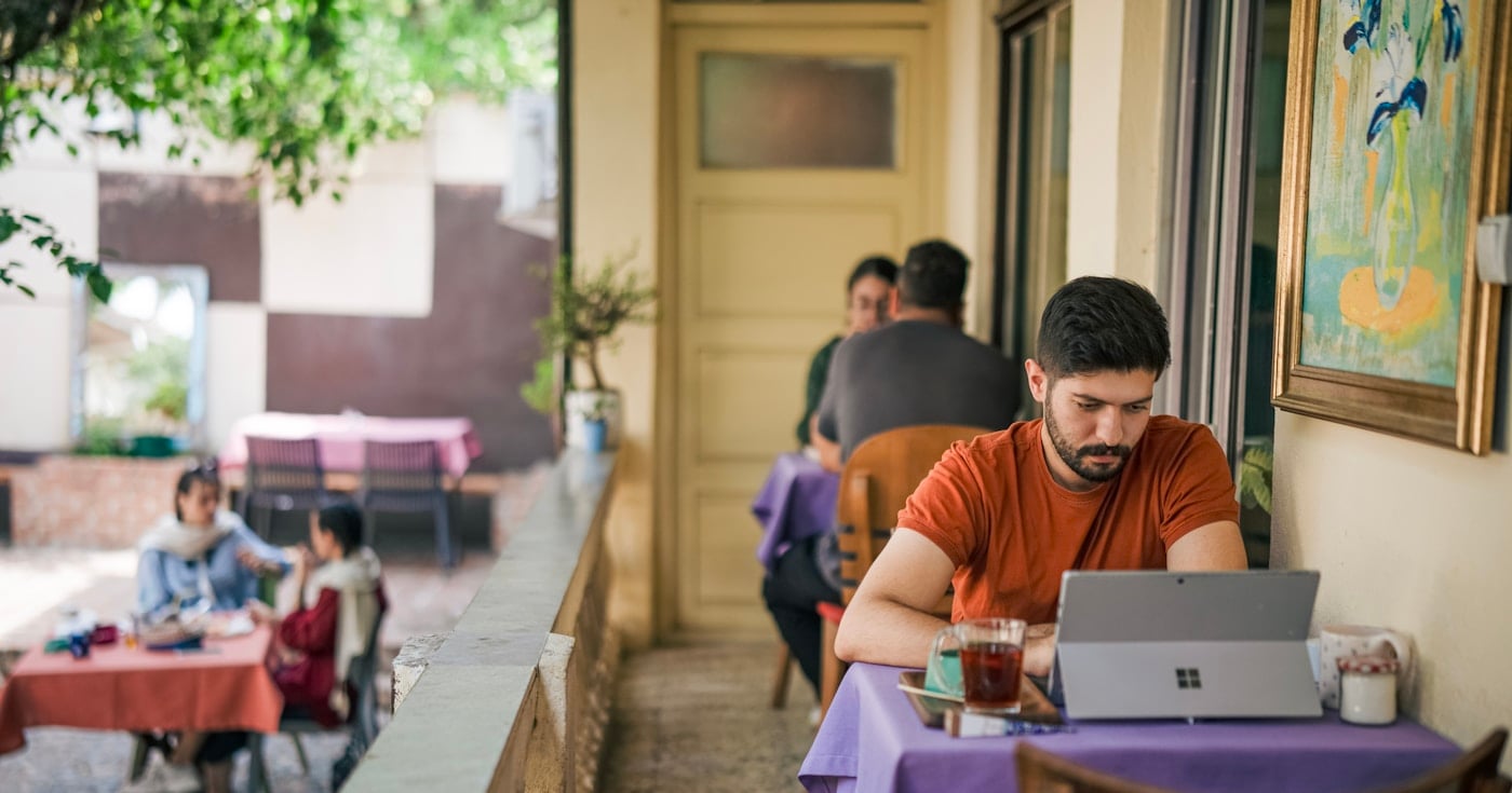 Person working on laptop at outdoor cafe - digital nomad lifestyle